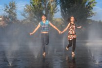 Азиатки прыгают на фонтанной воде — стоковое фото