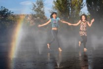 Les femmes asiatiques sautant sur l'eau de fontaine — Photo de stock