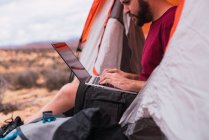 Мандрівник використовує ноутбук у наметі — стокове фото