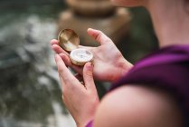 Close-up of female hands holding compass near lake — Stock Photo