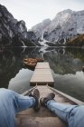 Gambe di uomo anonimo adagiate su gradini vicino al molo e alla superficie tranquilla di Pragser Wildsee nelle Dolomiti — Foto stock