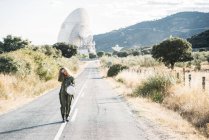 Astronauta feminina com cabelo encaracolado andando ao longo da estrada na natureza — Fotografia de Stock