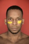 Portrait of of African American man with yellow smears of paint on face — Stock Photo