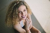Portrait of young curly woman with bright lips smiling outdoors — Stock Photo