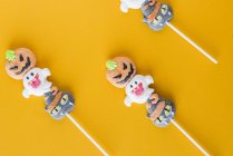 Caramelle di Halloween su bastoncini su sfondo arancione — Foto stock