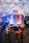 Дівчина в старому космічному шоломі і костюмі тримає фотоапарат — стокове фото