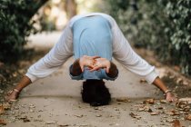 Barefoot woman performing Headstand on path in autumn garden — Stock Photo