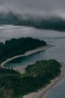 From above view of blue clean lake surrounded by hills with gray fog above — Stock Photo