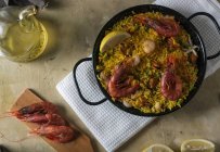 Traditional spanish paella marinera with rice, prawns, squid and mussels in pan with ingredients — Stock Photo