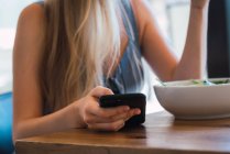 Женщина просматривает смартфон в кафе — стоковое фото