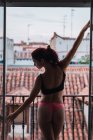Giovane donna in lingerie in posa sul balcone con vista sui vecchi tetti — Foto stock