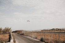 Aeronaves que voam a partir do aeroporto fechado por fio de segurança perto da estrada com carro em Mykonos — Fotografia de Stock