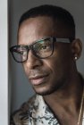 Primer plano de hombre afroamericano adulto serio en accesorios de oro y gafas mirando hacia otro lado - foto de stock