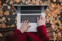Жінка з ноутбуком сидить на лавці — стокове фото