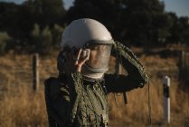 Female astronaut checking helmet in nature — Stock Photo