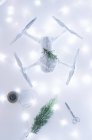 Drone enveloppé comme cadeau de Noël avec branche de sapin sur fond illuminé blanc — Photo de stock