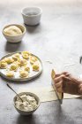 Main humaine préparant tortellini avec fromage cottage sur plateau gris — Photo de stock