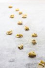 Close-up of uncooked tortellini in flour on grey tabletop — Stock Photo