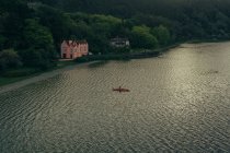 Зверху красиве тихе озеро з плаваючим човном і зеленим пишним лісом на березі — стокове фото
