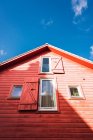 Janelas com persianas em casa vermelha de madeira no fundo do céu azul no dia ensolarado — Fotografia de Stock