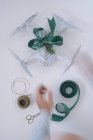 Mains masculines enveloppant drone comme cadeau de Noël avec branche de sapin et ruban vert sur fond blanc — Photo de stock