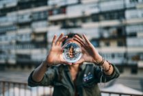 Woman holding crystal ball with reflection in city — Stock Photo