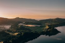Sauberer stiller See mit Reflexion der Bäume vor dem Hintergrund von Kratern und Bergen unter wolkenlosem Himmel — Stockfoto