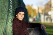 Портрет мальчика-подростка, опирающегося на забор на улице — стоковое фото