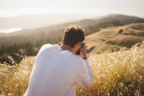 Man taking pictures in beautiful countryside — Stock Photo