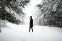 Mulher muito jovem em roupa elegante olhando para longe, enquanto de pé perto da árvore coberta de neve no dia frio no campo maravilhoso — Fotografia de Stock