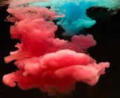 Nubes de humo vívidas de color rosa y azul sobre fondo negro - foto de stock