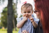 Woman holding cute baby girl in park — Stock Photo