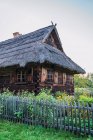 Petite clôture entourant la vieille cabane et le jardin en bois avec des fleurs dans la campagne estivale — Photo de stock