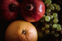 Korb mit Orangen, Trauben und Granatäpfeln auf dem Tisch — Stockfoto