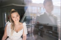 Bride looking to groom through a window — Stock Photo
