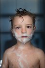 Ritratto di bambino con schiuma su viso e corpo in bagno — Foto stock