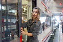 Mulher inclinada para fora trem na estação — Fotografia de Stock