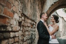 Couple marié étreignant près du vieux mur — Photo de stock