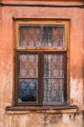 Crumbling wooden window on shabby wall of aged building — Stock Photo