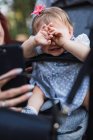 Женская рука показывает смартфон плачущей девочке, пытаясь развеселиться в парке — стоковое фото