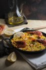 Traditional spanish paella marinera with rice, prawns, squid and mussels in pan with ingredients — Stock Photo