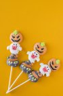 Bonbons d'Halloween sur bâtons sur fond orange — Photo de stock