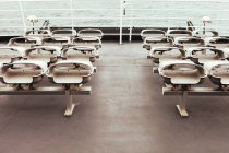 Ряд сложенных сидений на пустой палубе современного судна, плавающего в море — стоковое фото