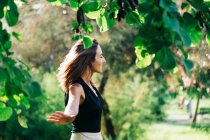 Donna allegra in piedi sotto l'albero nel parco — Foto stock