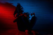 Jovem homem rastafarian africano gosta de ensaiar e joga udu, iluminação colorida vermelho e azul — Fotografia de Stock