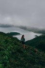 Frau steht auf hohem Hügel mit See darunter — Stockfoto