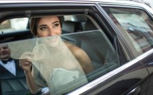 Lächelnde Braut schaut Bräutigam aus Auto an — Stockfoto