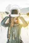 Confident woman in astronaut costume putting on helmet in sunlight — Stock Photo