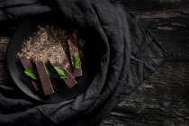 Pedaços de chocolate e pedaços com hortelã no fundo de madeira escura — Fotografia de Stock