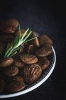 Dried almonds in bowl with rosemary sprig — Stock Photo